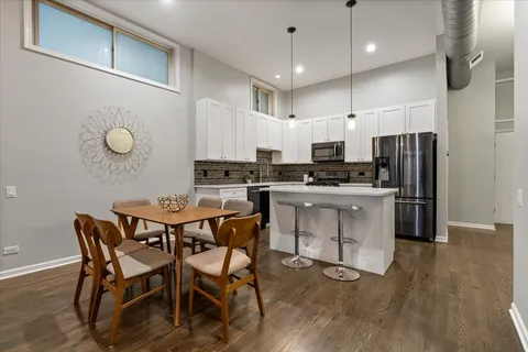 a kitchen with stainless steel appliances a dining table chairs stove and white cabinets