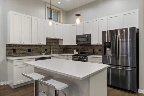 a kitchen with a refrigerator a microwave a sink and white cabinets