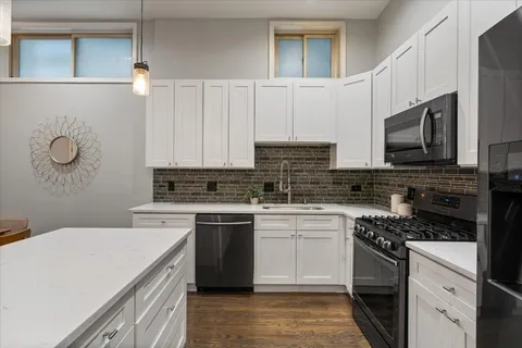 a kitchen with stainless steel appliances a sink a stove top oven a counter space and cabinets