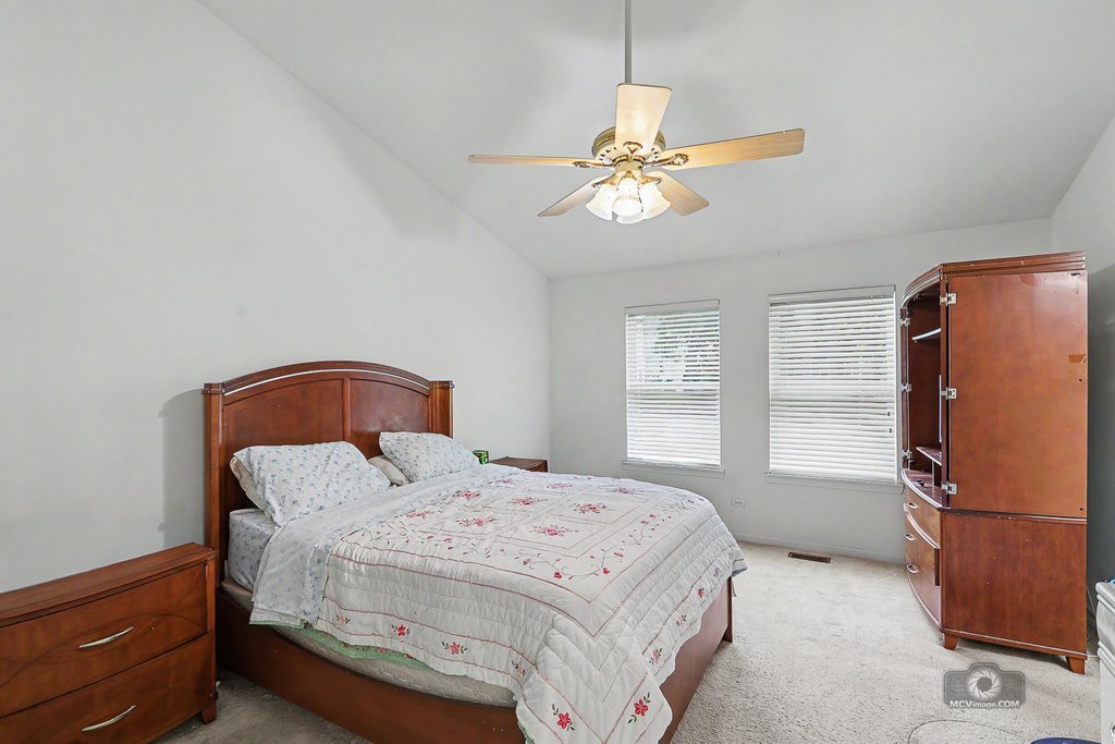 483 Elm Ridge Road Carpentersville, IL 60110 - Photo 19 of 31 a bedroom with a bed and a chandelier