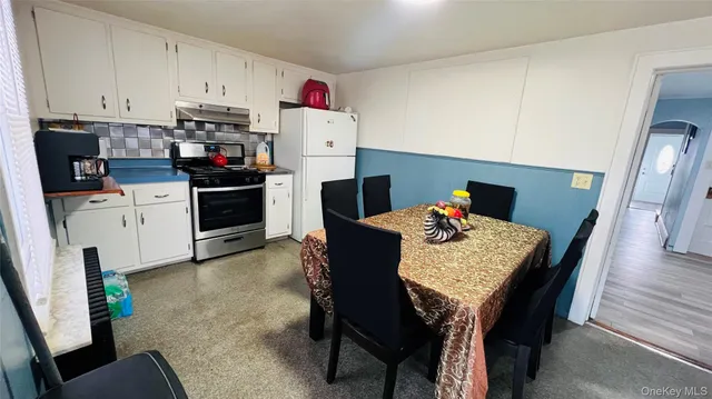 a kitchen with stainless steel appliances granite countertop a stove a refrigerator a dining table and chairs with wooden floor