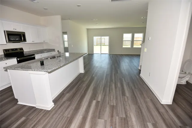 a living room with a couch wooden floor and a view of kitchen