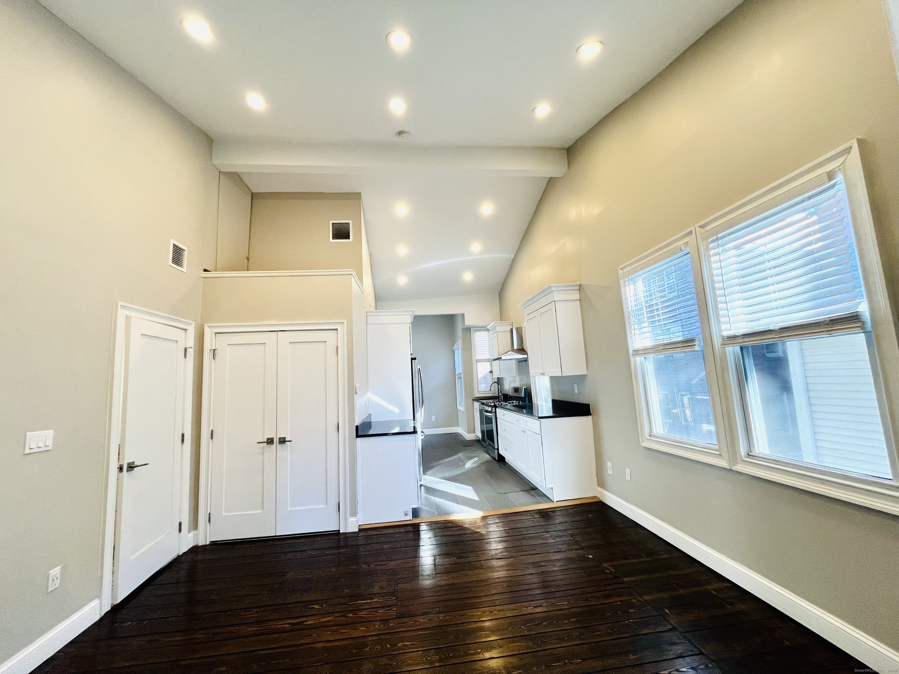 a view of an empty room with wooden floor and windows