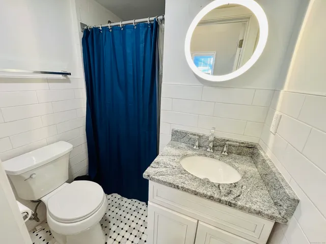 a bathroom with a granite countertop toilet and a sink