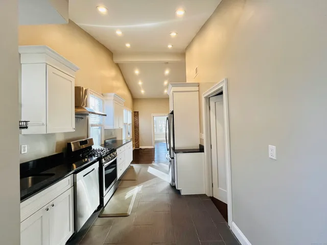 a kitchen with stainless steel appliances a refrigerator a sink and white cabinets