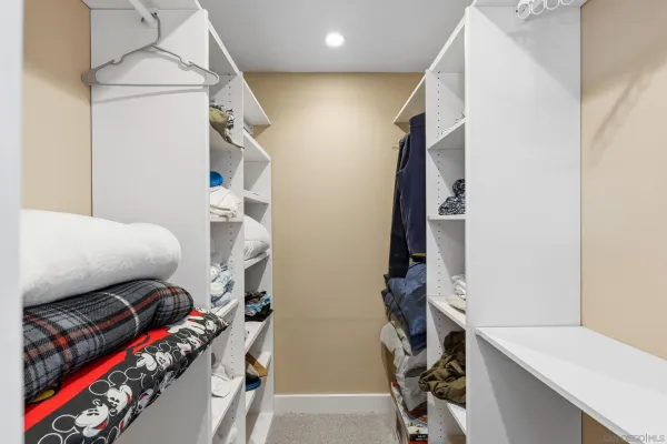 a view of walk in closet with clothes and shoes