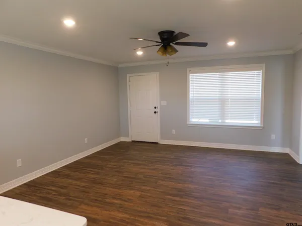 a view of an empty room with a window and wooden floor