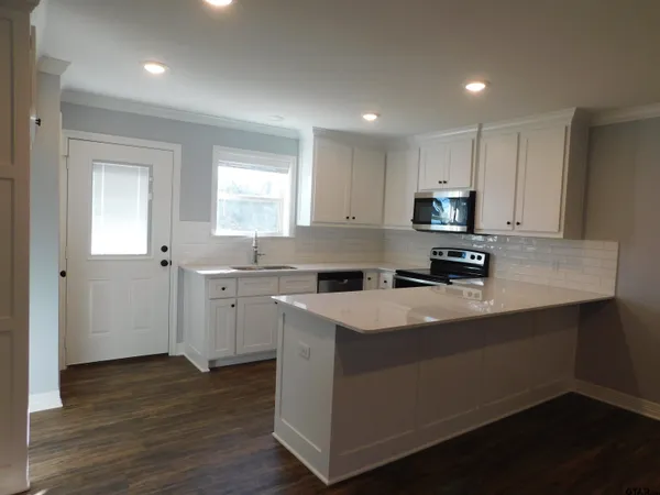a kitchen with cabinets appliances a sink and a window