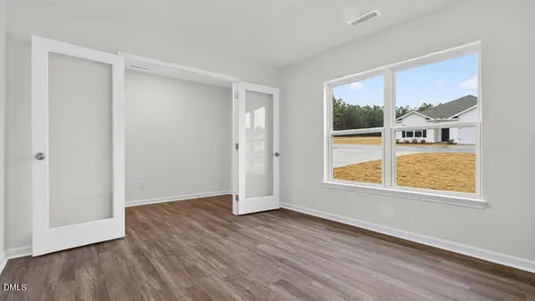 a view of an empty room with wooden floor and a window