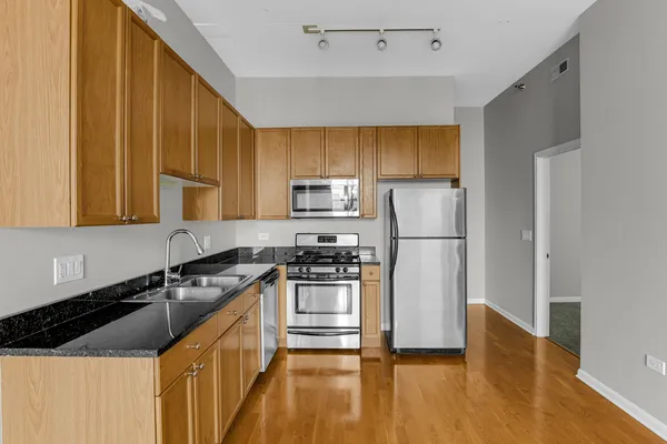 a kitchen with granite countertop a refrigerator stove and sink