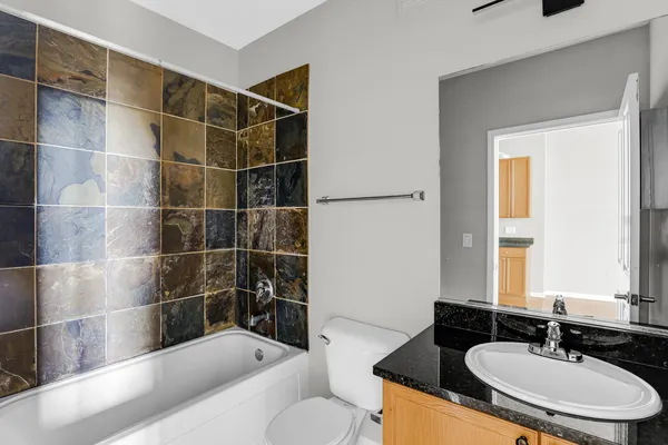 a bathroom with a granite countertop sink a toilet a mirror and shower