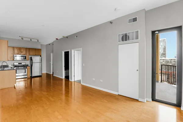 a view of an empty room with kitchen view and a window