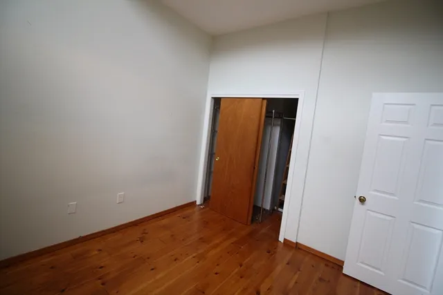 an empty room with wooden floor and closet
