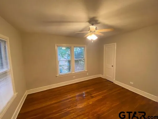 en view of an empty room with wooden floor and a window