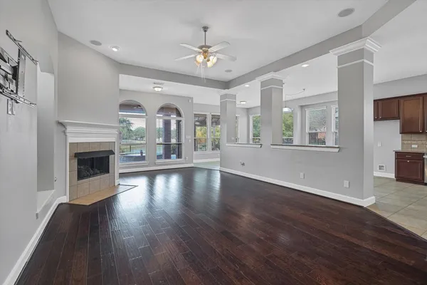 an empty room with fireplace wooden floor chandelier and windows