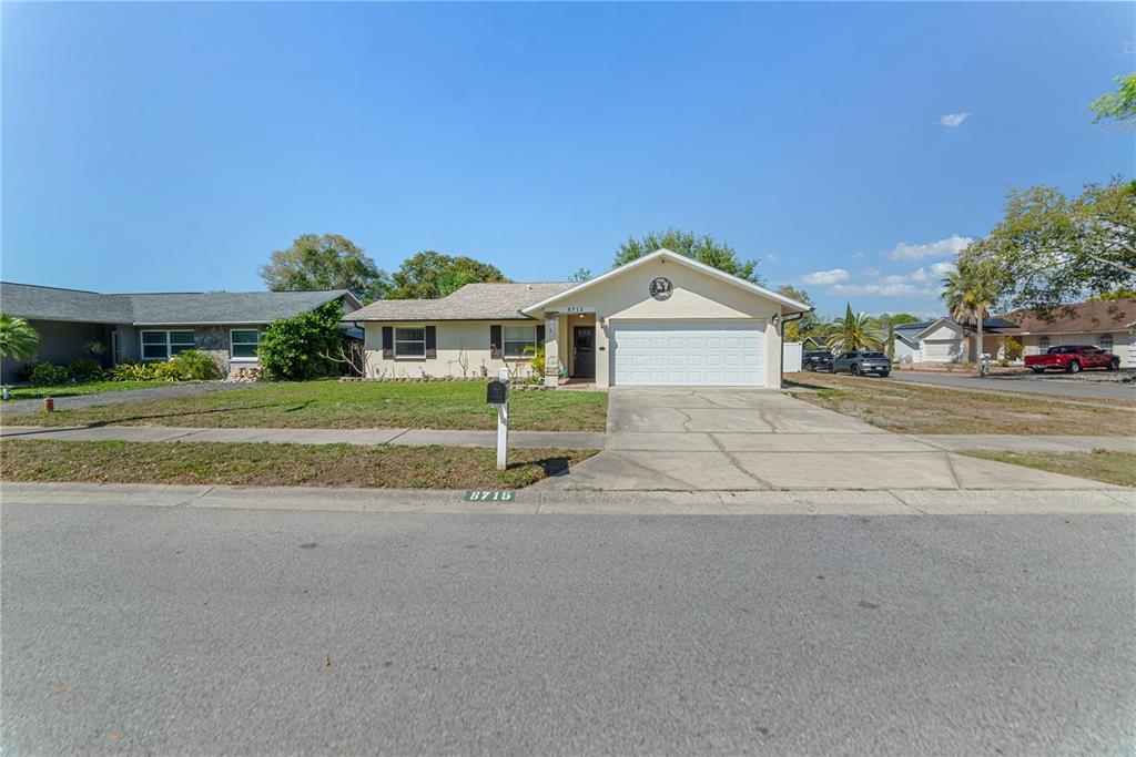 8715 Huntsman Lane Port Richey, FL 34668 - Photo 5 of 54 a front view of a house with a garden and yard