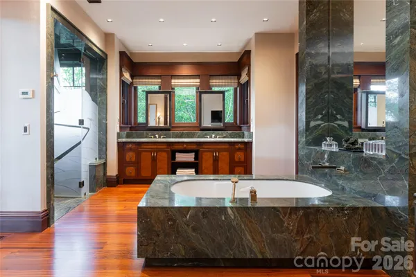 a living room with stainless steel appliances kitchen island granite countertop a refrigerator a stove and a sink with wooden floor