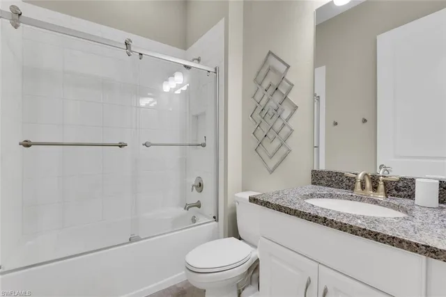 a bathroom with a granite countertop sink a toilet and shower
