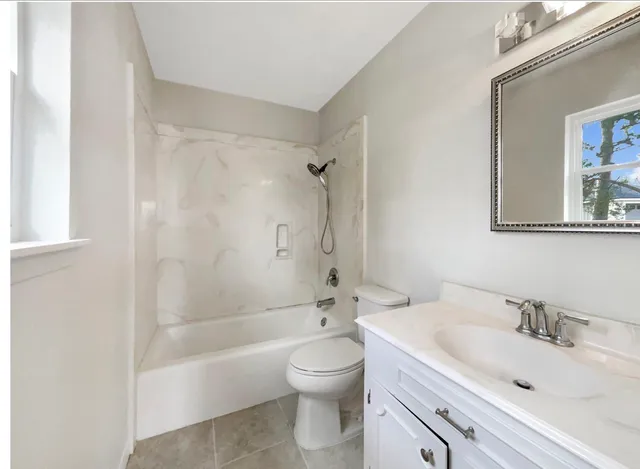 a bathroom with a bathtub shower sink mirror and toilet