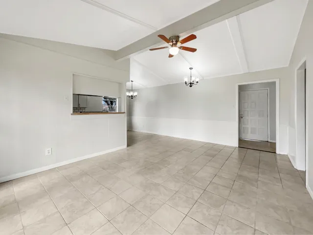 an empty room with white walls and ceiling fan