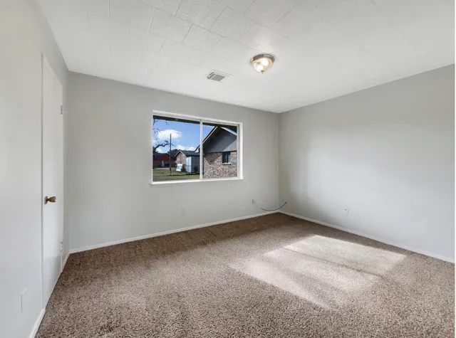a view of an empty room with closet and a window