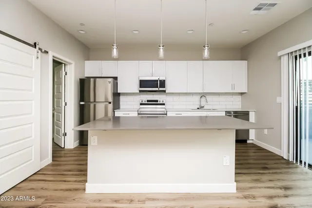 a kitchen with stainless steel appliances a refrigerator a stove a sink dishwasher and a refrigerator with wooden floor