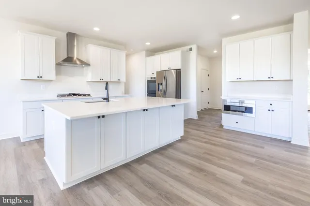 a kitchen with stainless steel appliances white cabinets and wooden floors