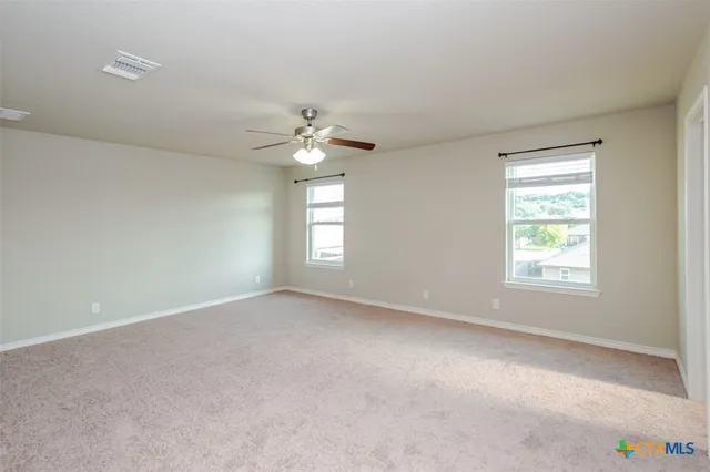 an empty room with windows and fan