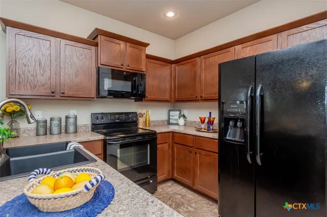 a kitchen with stainless steel appliances granite countertop a stove a sink dishwasher and a refrigerator