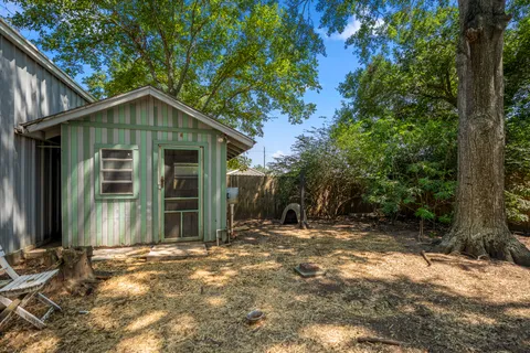 a view of a house with a small yard and large tree