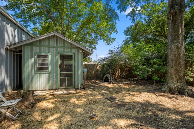 a view of a house with a small yard and large tree