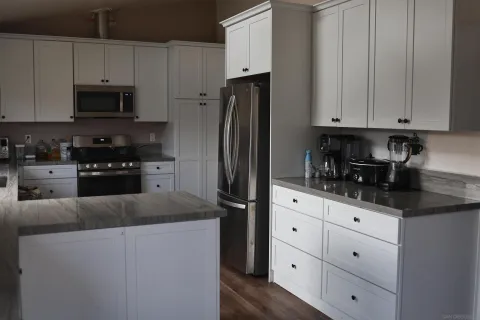 a kitchen with granite countertop white cabinets and stainless steel appliances