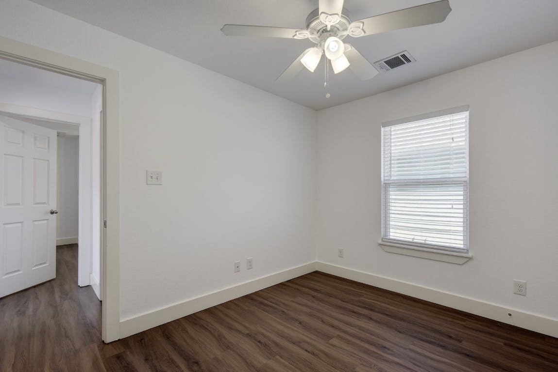 1311 East 52nd Street, Unit 3 Austin, TX 78723 - Photo 12 of 20 an empty room with wooden floor chandelier fan and windows