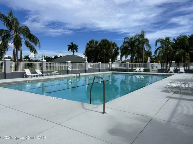 a view of swimming pool with a yard and palm trees