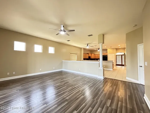 a view of a big room with wooden floor and a kitchen