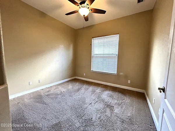 an empty room with windows and fan