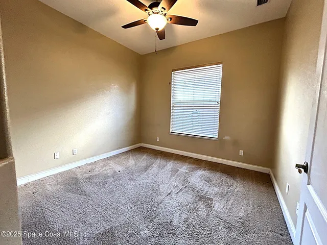 an empty room with windows and fan