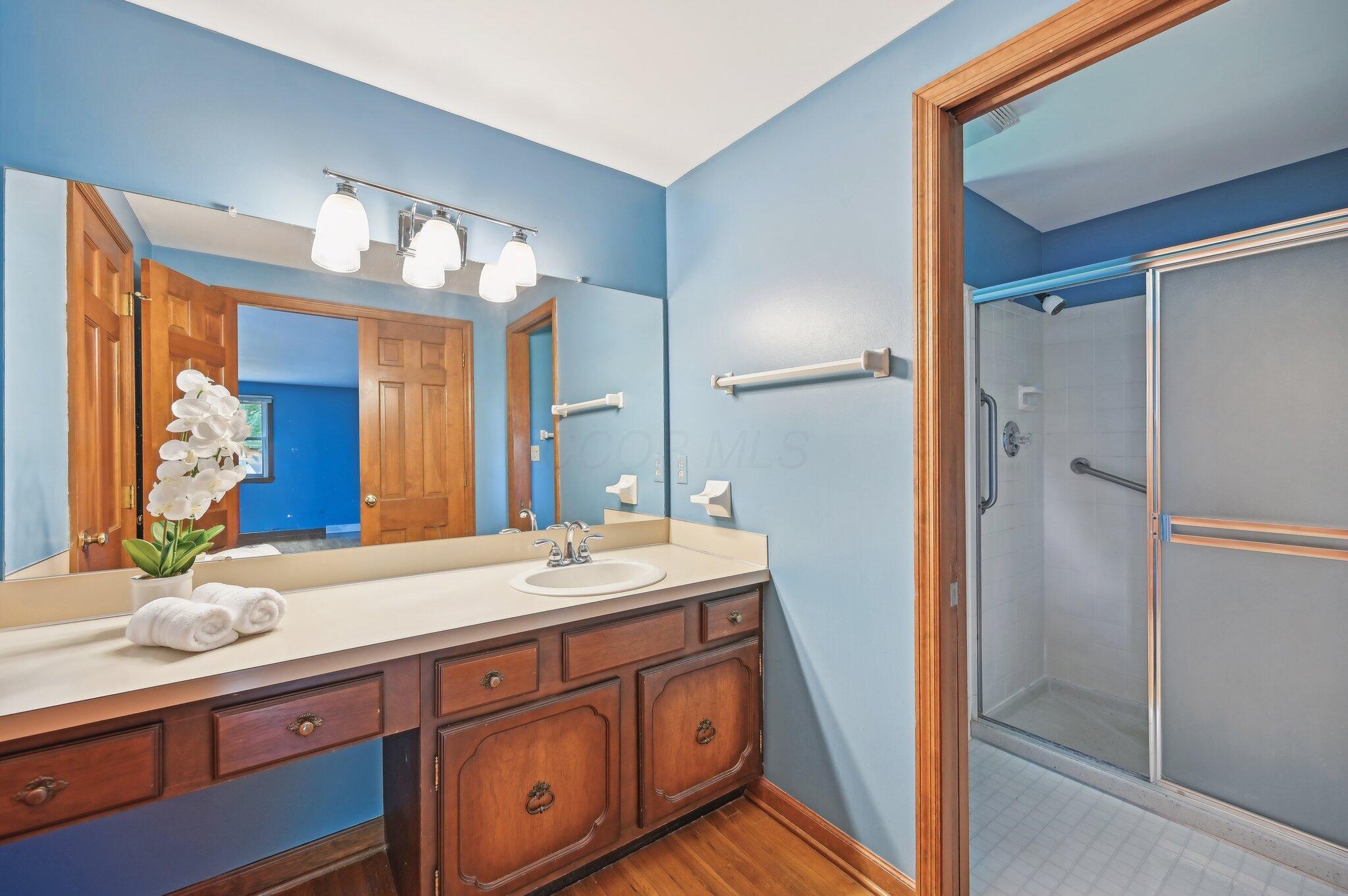 5917 Rocky Rill Road Columbus, OH 43235 - Photo 25 of 47 Primary bathroom with a wide vanity, three-light fixture, and step-in shower with sliding glass door.