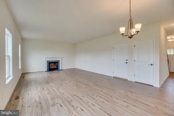a view of a room with wooden floor ceiling fan and window