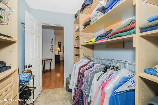 a view of walk in closet with clothes and shoes