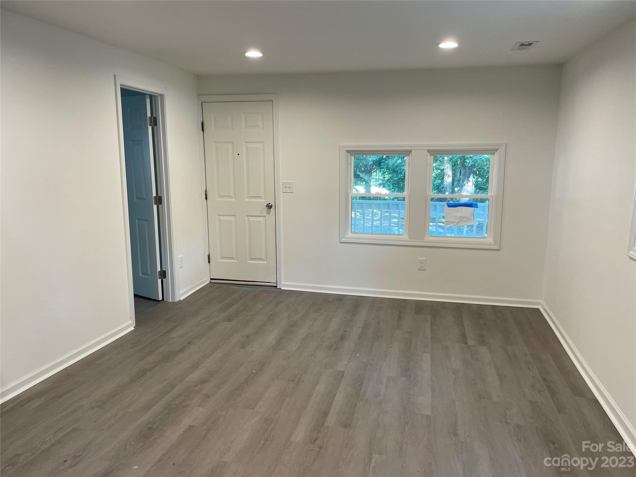205 Jerome Street Wingate, NC 28174 - Photo 3 of 7 an empty room with wooden floor and windows