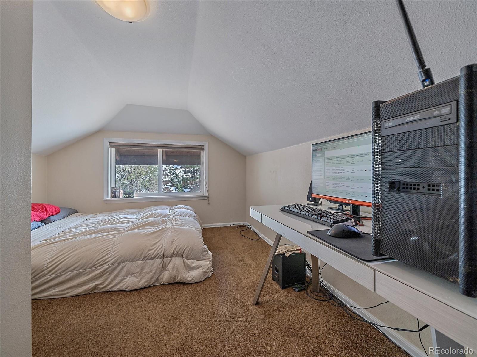 24293 Running Deer Road Conifer, CO 80433 - Photo 14 of 33 a bedroom with a bed and a window