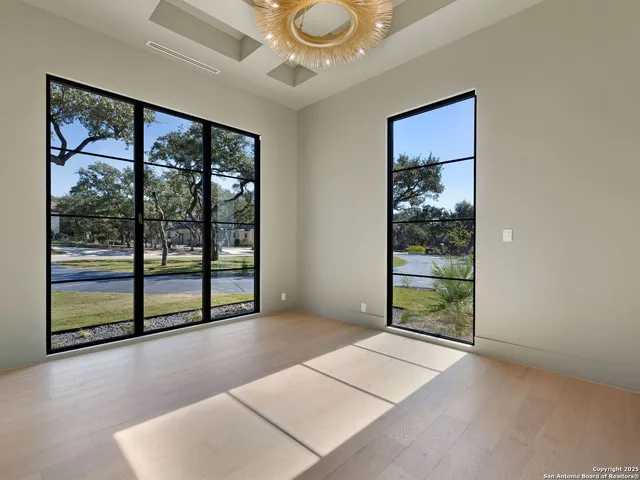 a view of an empty room with a window and wooden floor