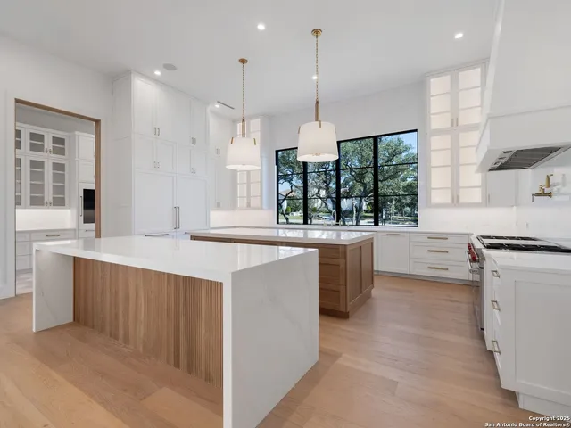 a large kitchen with kitchen island a large counter top space a sink stainless steel appliances and windows