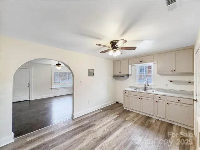 an empty room with wooden floor chandelier and windows