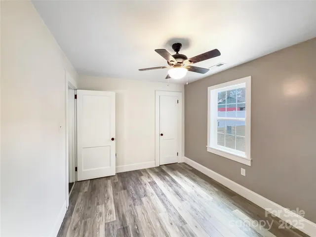 a view of empty room with wooden floor and fan