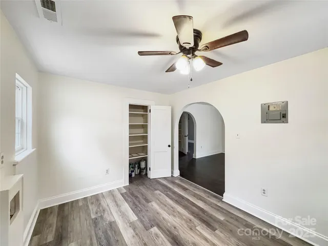 a view of empty room with wooden floor and fan