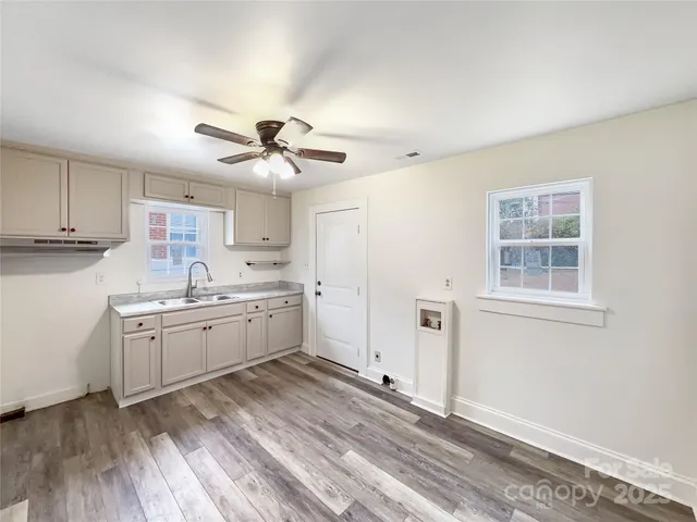 a kitchen with granite countertop a stove a sink and white cabinets with wooden floor
