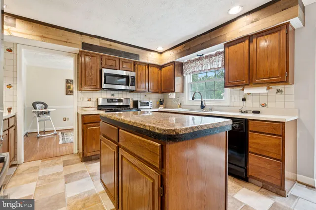 a kitchen with stainless steel appliances granite countertop a sink stove microwave and refrigerator