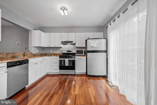 a kitchen with a refrigerator a stove top oven a sink and cabinets
